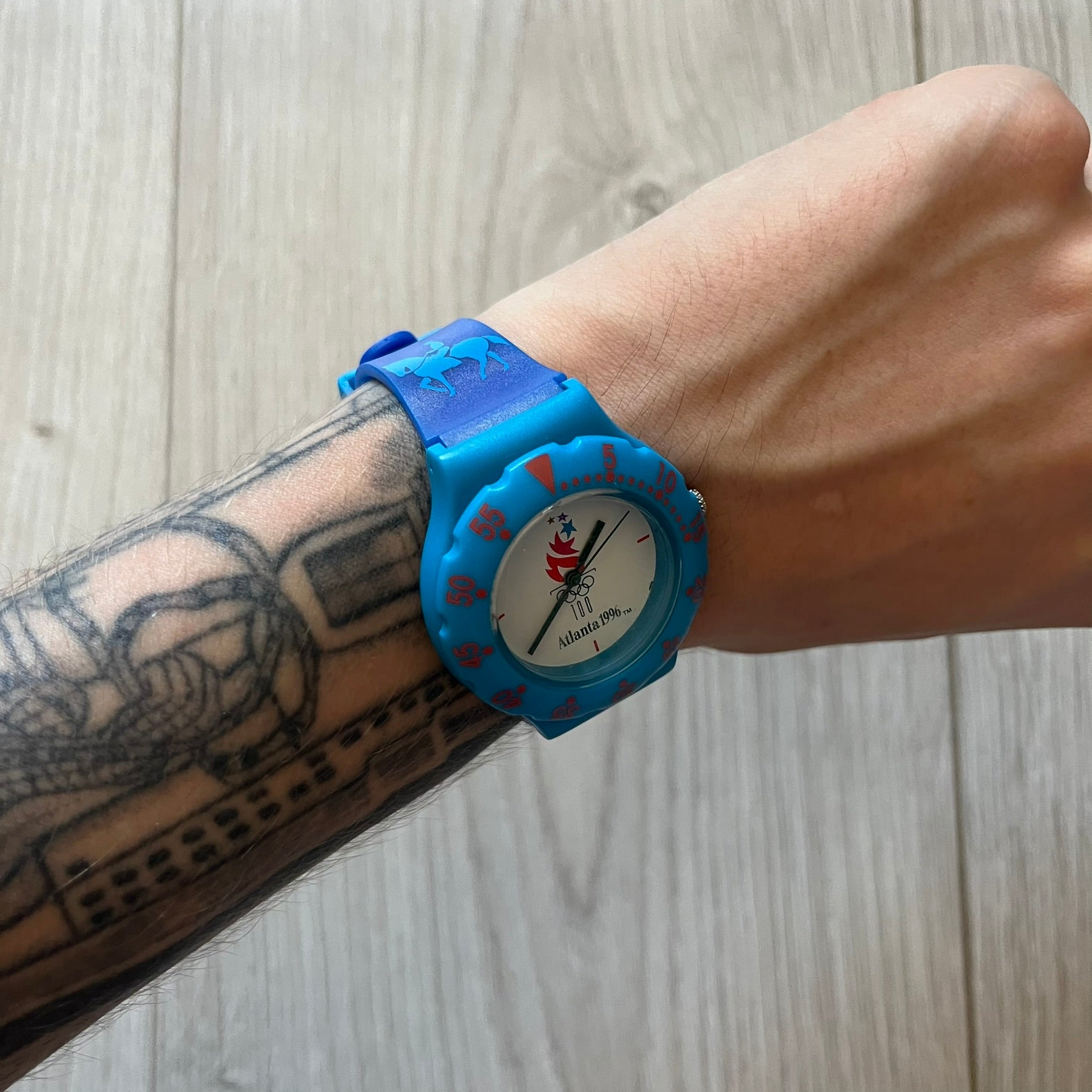 McDonald’s Atlanta 1996 Olympics analog watch with a dark blue strap featuring light blue sport-themed motifs. The dial is white with blue and red accents, showcasing the official Atlanta 1996 logo. A nostalgic collectible celebrating the iconic Olympic collaboration.