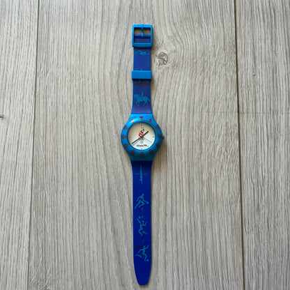 McDonald’s Atlanta 1996 Olympics analog watch with a dark blue strap featuring light blue sport-themed motifs. The dial is white with blue and red accents, showcasing the official Atlanta 1996 logo. A nostalgic collectible celebrating the iconic Olympic collaboration.