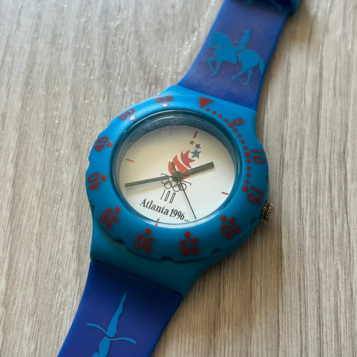 McDonald’s Atlanta 1996 Olympics analog watch with a dark blue strap featuring light blue sport-themed motifs. The dial is white with blue and red accents, showcasing the official Atlanta 1996 logo. A nostalgic collectible celebrating the iconic Olympic collaboration.