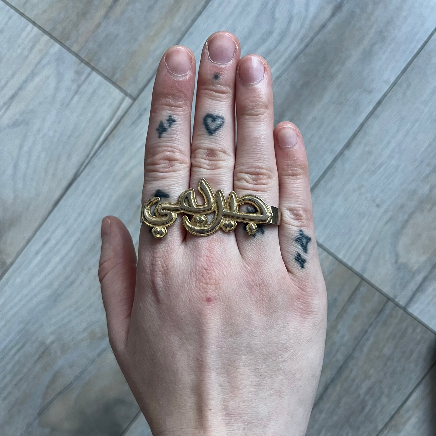 Melody Ehsani x Jeremy Scott 2013 Arabic Three Finger Ring is a gold-tone three-finger ring from the 2013 Fearless collection by Melody Ehsani and Jeremy Scott. The ring features the name “Jeremy” written in Arabic script across the three connected bands. Released in 2013, the piece originally retailed for $100.