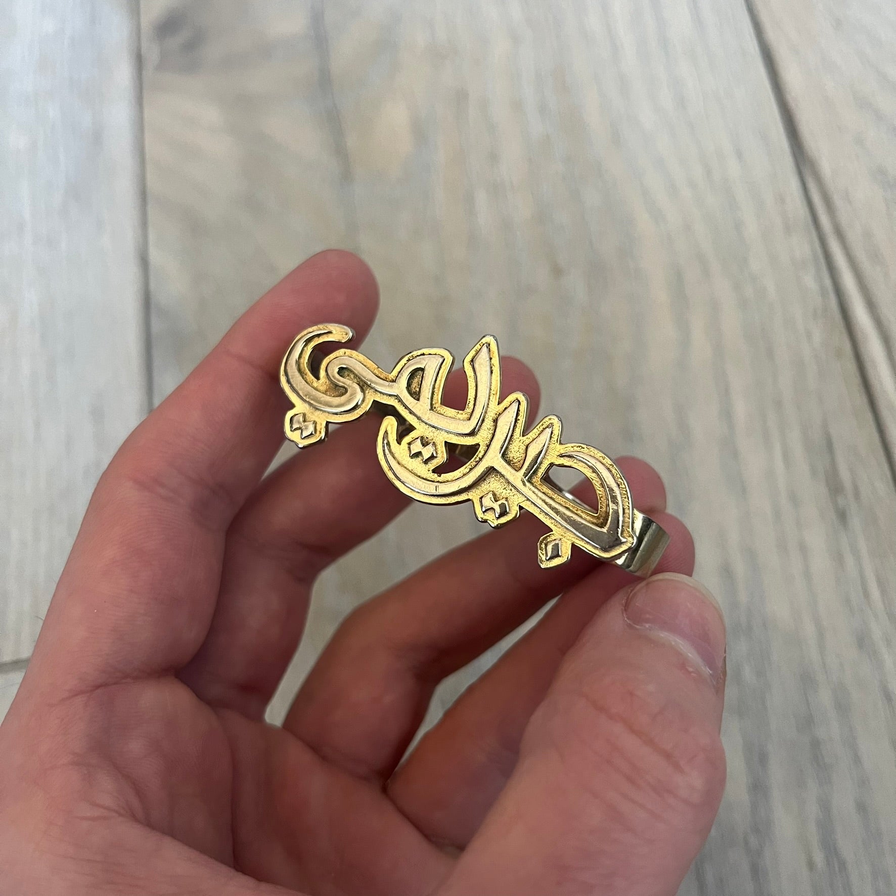 Melody Ehsani x Jeremy Scott 2013 Arabic Three Finger Ring is a gold-tone three-finger ring from the 2013 Fearless collection by Melody Ehsani and Jeremy Scott. The ring features the name “Jeremy” written in Arabic script across the three connected bands. Released in 2013, the piece originally retailed for $100.