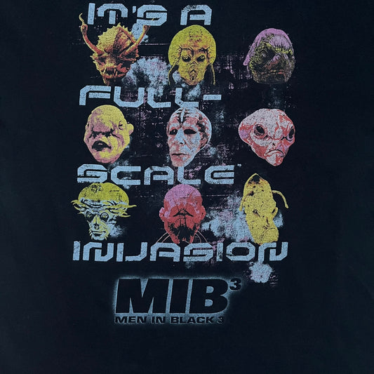 Black Men In Black 3 T-shirt from 2012, featuring a front graphic with nine colorful alien faces arranged in a 3×3 grid. The phrase “It’s a Full Scale Invasion” is printed between the faces, with a white Men In Black 3 logo placed below. Finished with an official MIB neck tag, short sleeves, and a standard crew neckline.