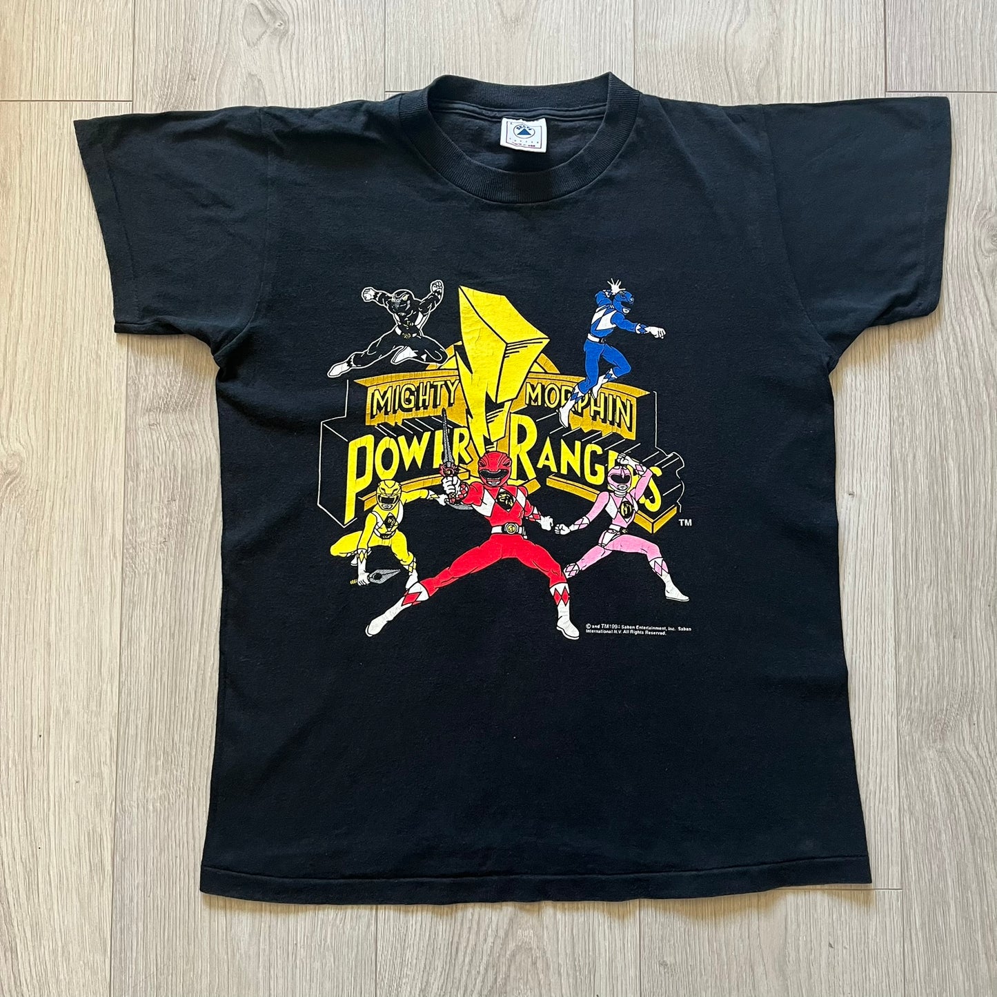 1994 Power Rangers tee with striking full-team graphic, officially licensed by Saban Entertainment. Crafted on a Delta USA-made blank with single stitch finish for authentic vintage feel. Perfect for fans and collectors of classic ‘90s TV.