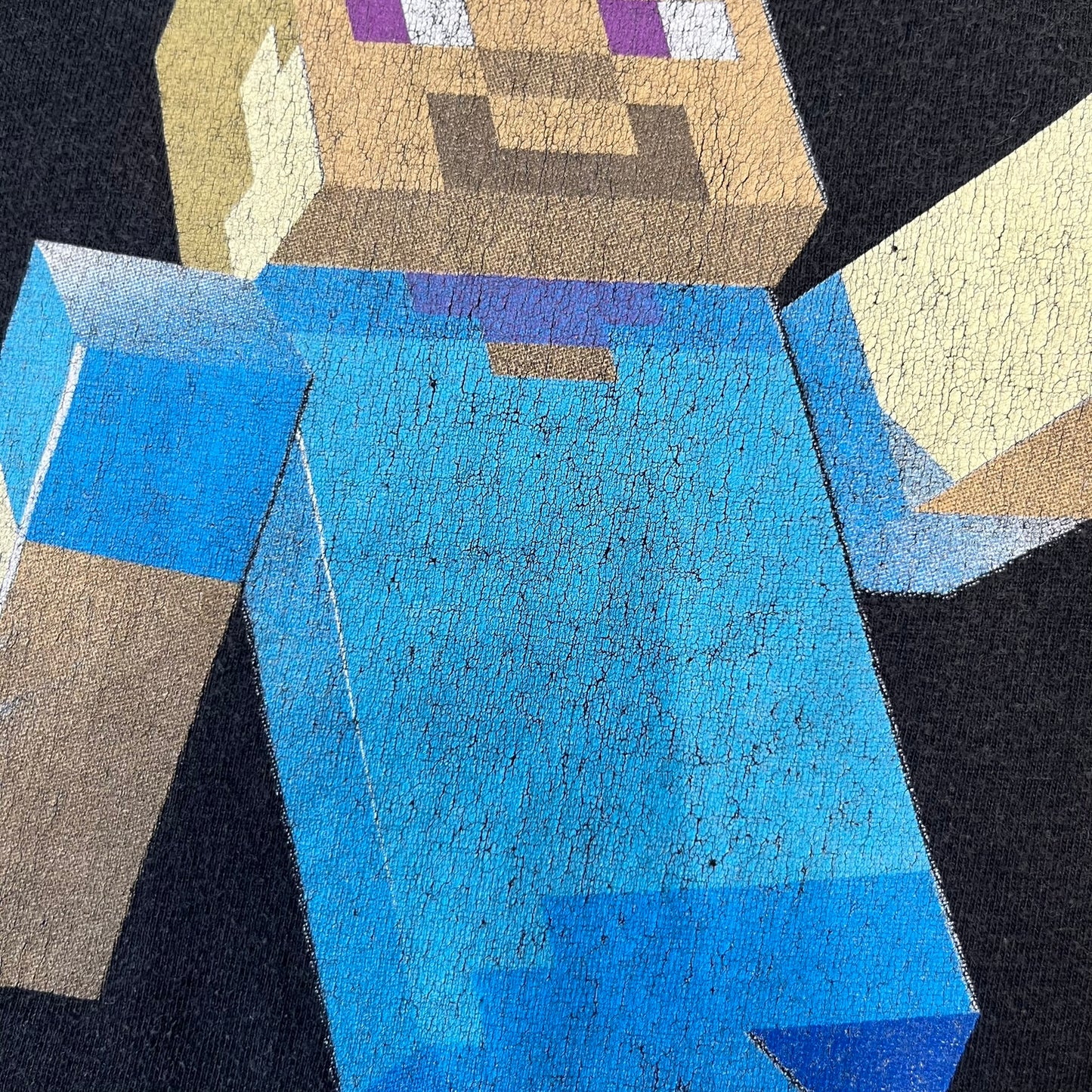 Minecraft 2012 Xbox 360 Black Promo Tee features a black design with Steve from Minecraft walking while holding a diamond pickaxe on the front. The sleeve has a white Xbox 360 logo, while the back features three white gaming-related logos including Mojang. A promotional release from 2012.
