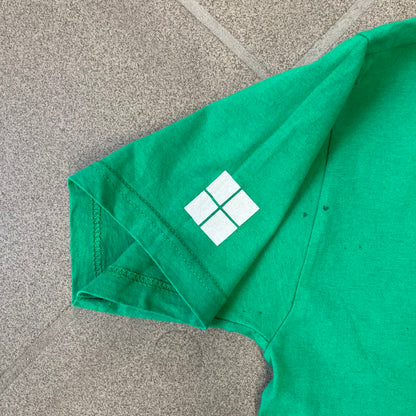 Minecraft 2015 Minecon London Green Tee is a green T-shirt made for Minecon 2015 in London, featuring Big Ben with a Creeper face on the front, with “Minecon London July 4-5” text in Minecraft-style lettering. The upper back displays “Minecon” with “Thanks for Playing” text below, while the sleeves carry a Mojang logo on one side and a Microsoft logo on the other.