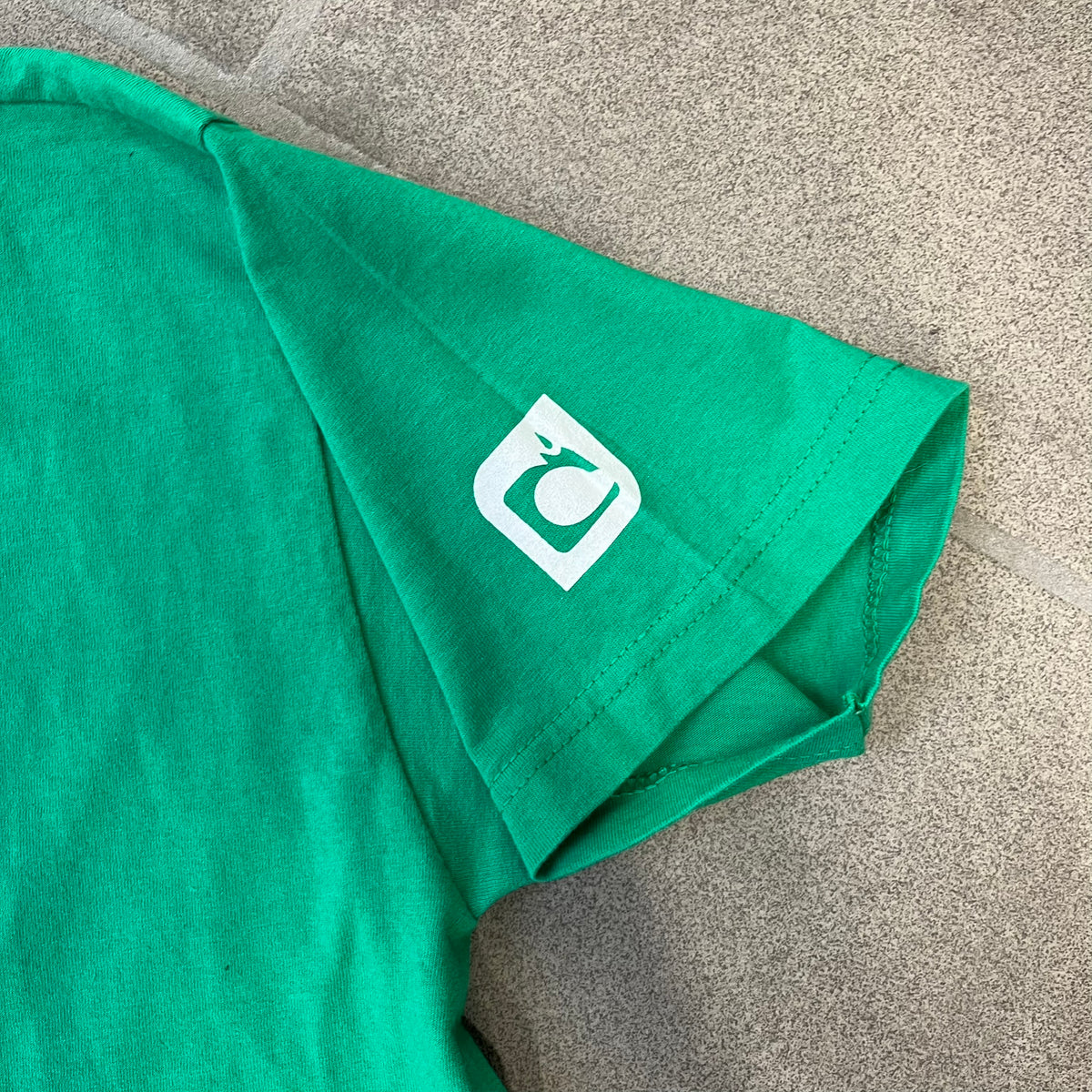 Minecraft 2015 Minecon London Green Tee is a green T-shirt made for Minecon 2015 in London, featuring Big Ben with a Creeper face on the front, with “Minecon London July 4-5” text in Minecraft-style lettering. The upper back displays “Minecon” with “Thanks for Playing” text below, while the sleeves carry a Mojang logo on one side and a Microsoft logo on the other.