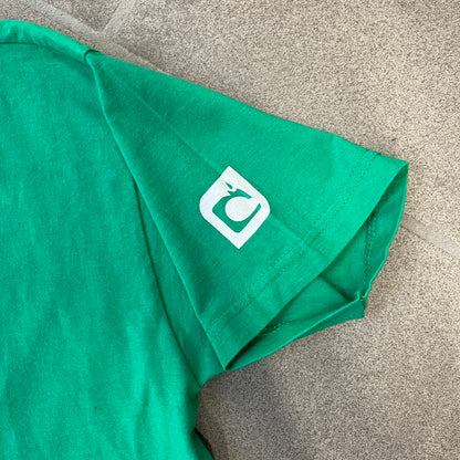Minecraft 2015 Minecon London Green Tee is a green T-shirt made for Minecon 2015 in London, featuring Big Ben with a Creeper face on the front, with “Minecon London July 4-5” text in Minecraft-style lettering. The upper back displays “Minecon” with “Thanks for Playing” text below, while the sleeves carry a Mojang logo on one side and a Microsoft logo on the other.