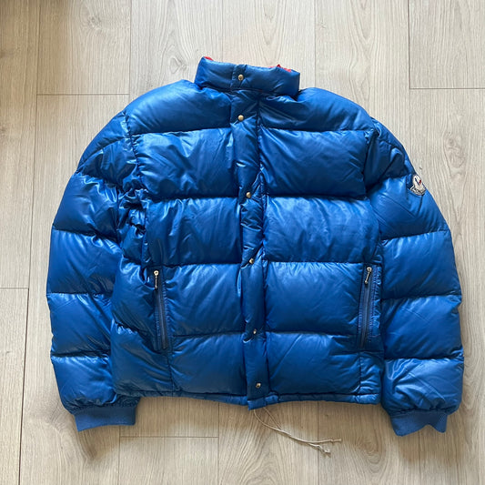 Vintage 1980s Moncler Grenoble down jacket in blue with a contrasting red lining. Features a foldable thin hood hidden in the back, silver-tone buttons and zippers, and the original Moncler patch on the sleeve. A rare French-made piece with authentic Grenoble labels, distinct from the brand’s modern ski line.