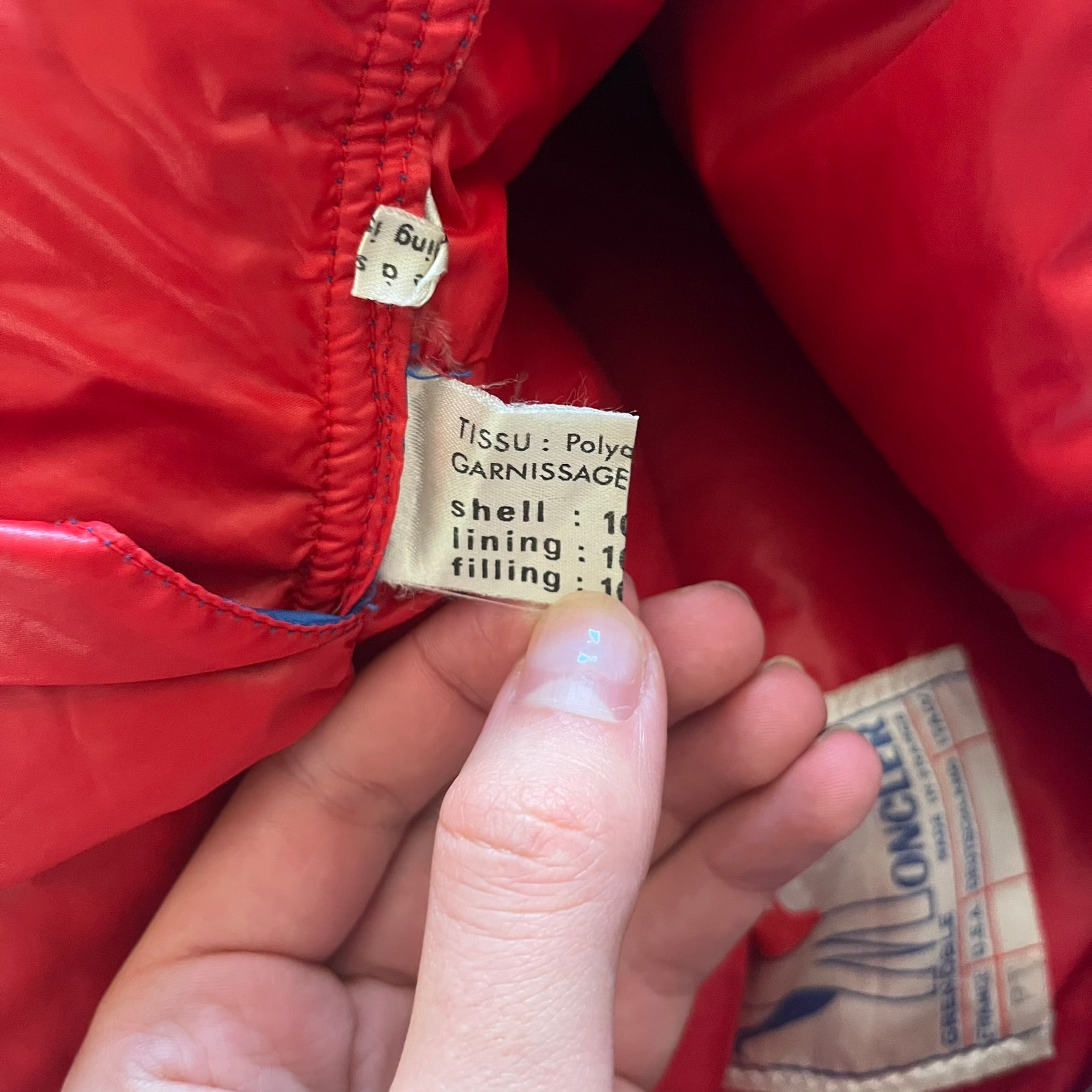 Vintage 1980s Moncler Grenoble down jacket in blue with a contrasting red lining. Features a foldable thin hood hidden in the back, silver-tone buttons and zippers, and the original Moncler patch on the sleeve. A rare French-made piece with authentic Grenoble labels, distinct from the brand’s modern ski line.