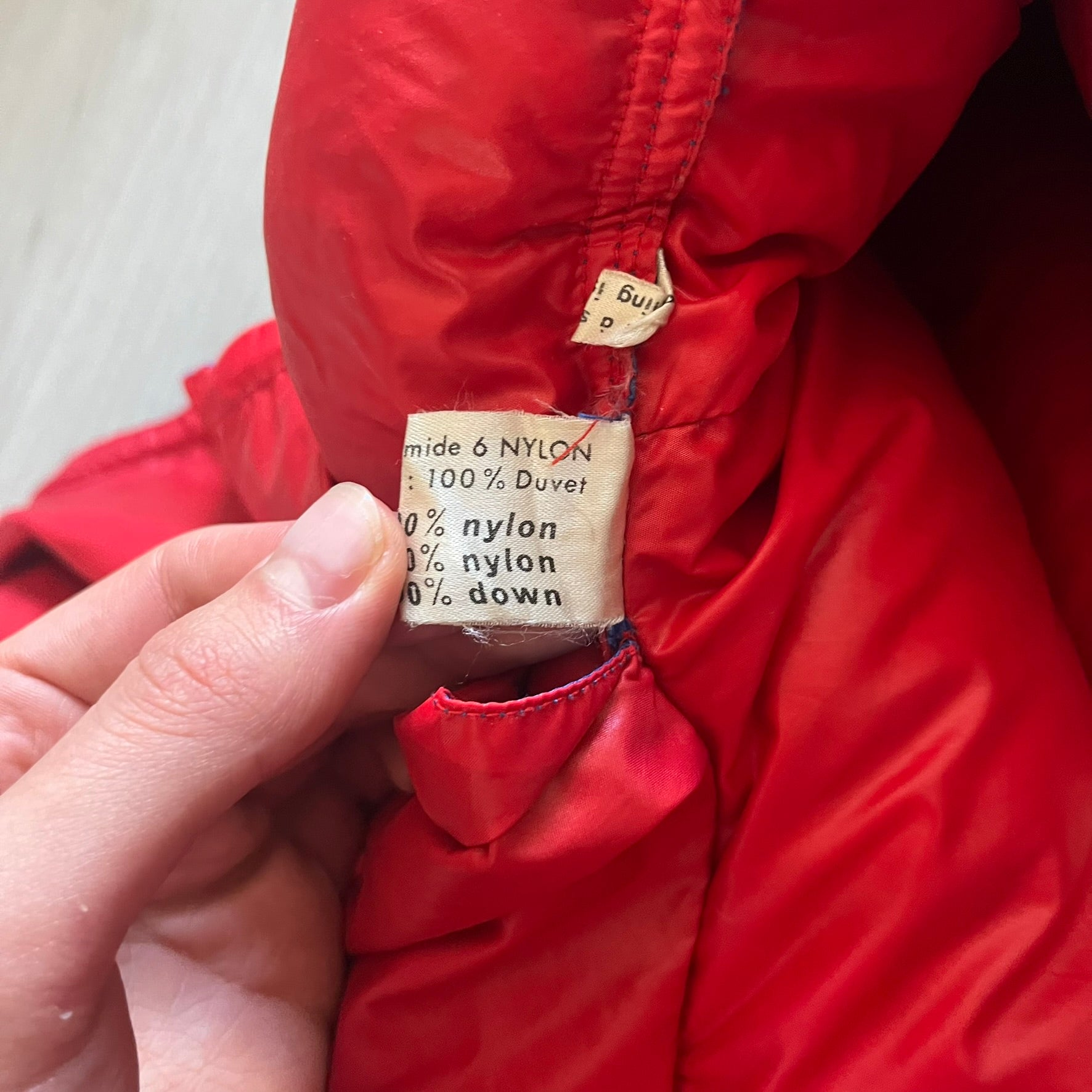 Vintage 1980s Moncler Grenoble down jacket in blue with a contrasting red lining. Features a foldable thin hood hidden in the back, silver-tone buttons and zippers, and the original Moncler patch on the sleeve. A rare French-made piece with authentic Grenoble labels, distinct from the brand’s modern ski line.