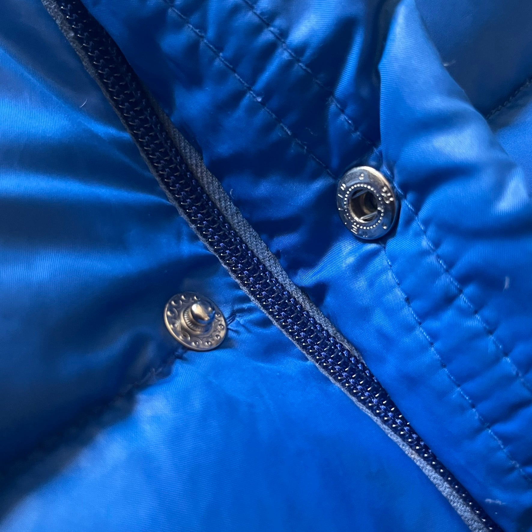 Vintage 1980s Moncler Grenoble down jacket in blue with a contrasting red lining. Features a foldable thin hood hidden in the back, silver-tone buttons and zippers, and the original Moncler patch on the sleeve. A rare French-made piece with authentic Grenoble labels, distinct from the brand’s modern ski line.