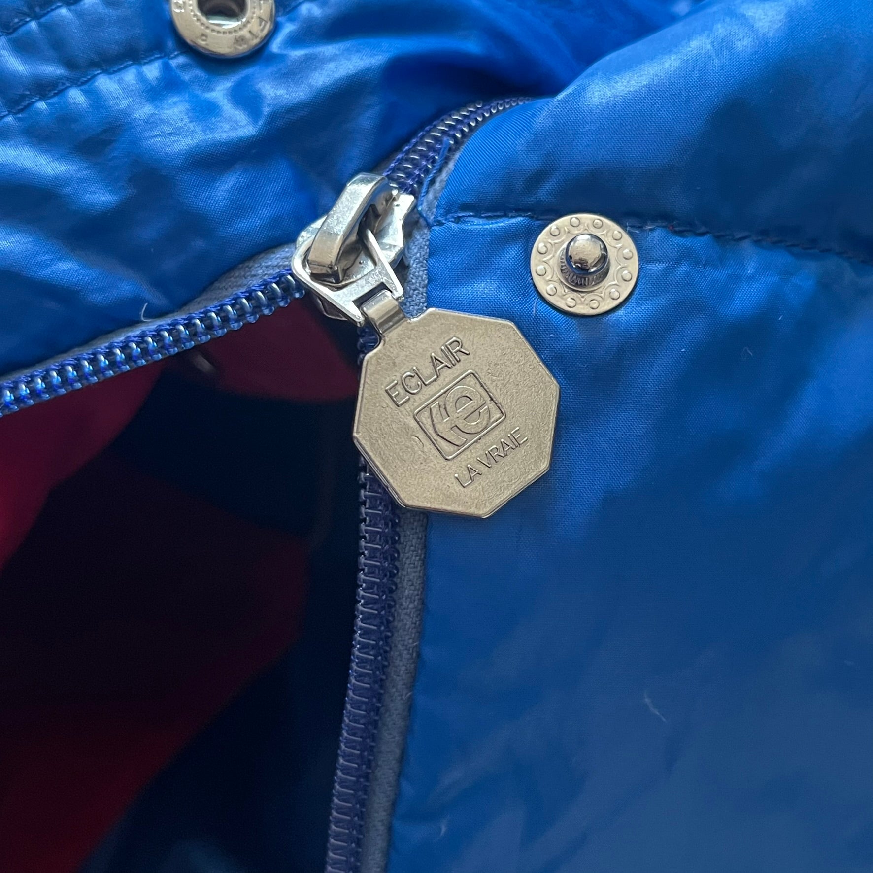 Vintage 1980s Moncler Grenoble down jacket in blue with a contrasting red lining. Features a foldable thin hood hidden in the back, silver-tone buttons and zippers, and the original Moncler patch on the sleeve. A rare French-made piece with authentic Grenoble labels, distinct from the brand’s modern ski line.