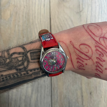 Monster High Red & Pink Kids Watch is a children’s wristwatch featuring a red strap printed with Monster High logos and character graphics. The watch has a silver-tone case with a pink dial, black numerals, and white hands, along with a Monster High character graphic and logo on the face. It comes packaged in a pink box with full Monster High branding.