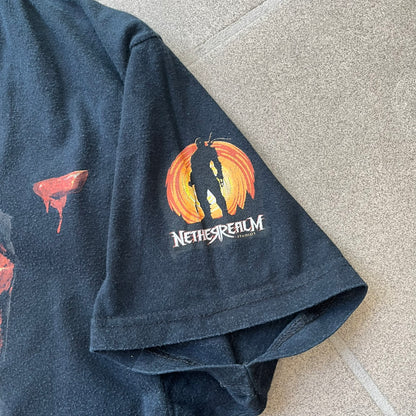 Mortal Kombat 9 Fatality Truck Tour 2011 Tee features a black T-shirt with a front graphic of a broken red ribcage and heart on a blood-covered surface. A vertical “Fatality” graphic is printed along the side, with Warner Bros. licensing text underneath the heart. One sleeve features the NetherRealm Studios logo. The back has the classic “Finish Him” text, Mortal Kombat logo, and matching licensing details.
