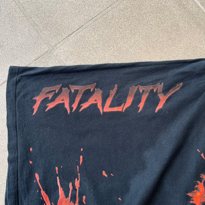 Mortal Kombat 9 Fatality Truck Tour 2011 Tee features a black T-shirt with a front graphic of a broken red ribcage and heart on a blood-covered surface. A vertical “Fatality” graphic is printed along the side, with Warner Bros. licensing text underneath the heart. One sleeve features the NetherRealm Studios logo. The back has the classic “Finish Him” text, Mortal Kombat logo, and matching licensing details.
