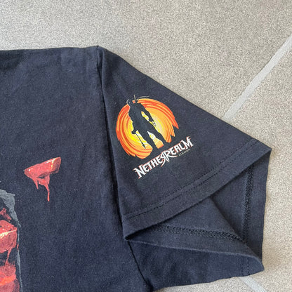 Mortal Kombat 9 Fatality Truck Tour 2011 Tee features a black T-shirt with a front graphic of a broken red ribcage and heart on a blood-covered surface. A vertical “Fatality” graphic is printed along the side, with Warner Bros. licensing text underneath the heart. One sleeve features the NetherRealm Studios logo. The back has the classic “Finish Him” text, Mortal Kombat logo, and matching licensing details.
