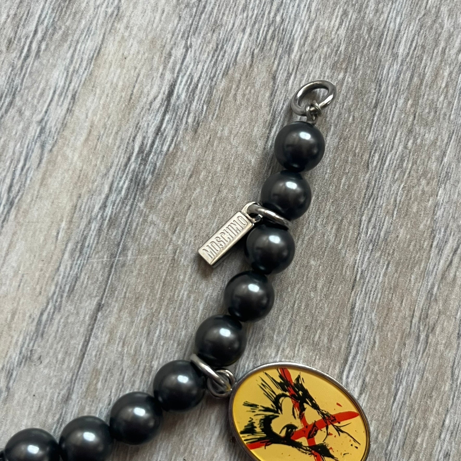 Moschino 2000’s “Time 4 Holy” Pendants Bracelet Watch is a bracelet watch from Moschino featuring a beaded construction with black pearly beads and multiple hanging religious-themed charms. The bracelet includes Madonna and holy figure pendants, with one charm functioning as a small hour-and-minute watch. Made in Italy in the early 2000s, the piece uses a pendant-style layout combining jewelry elements with a functional watch.