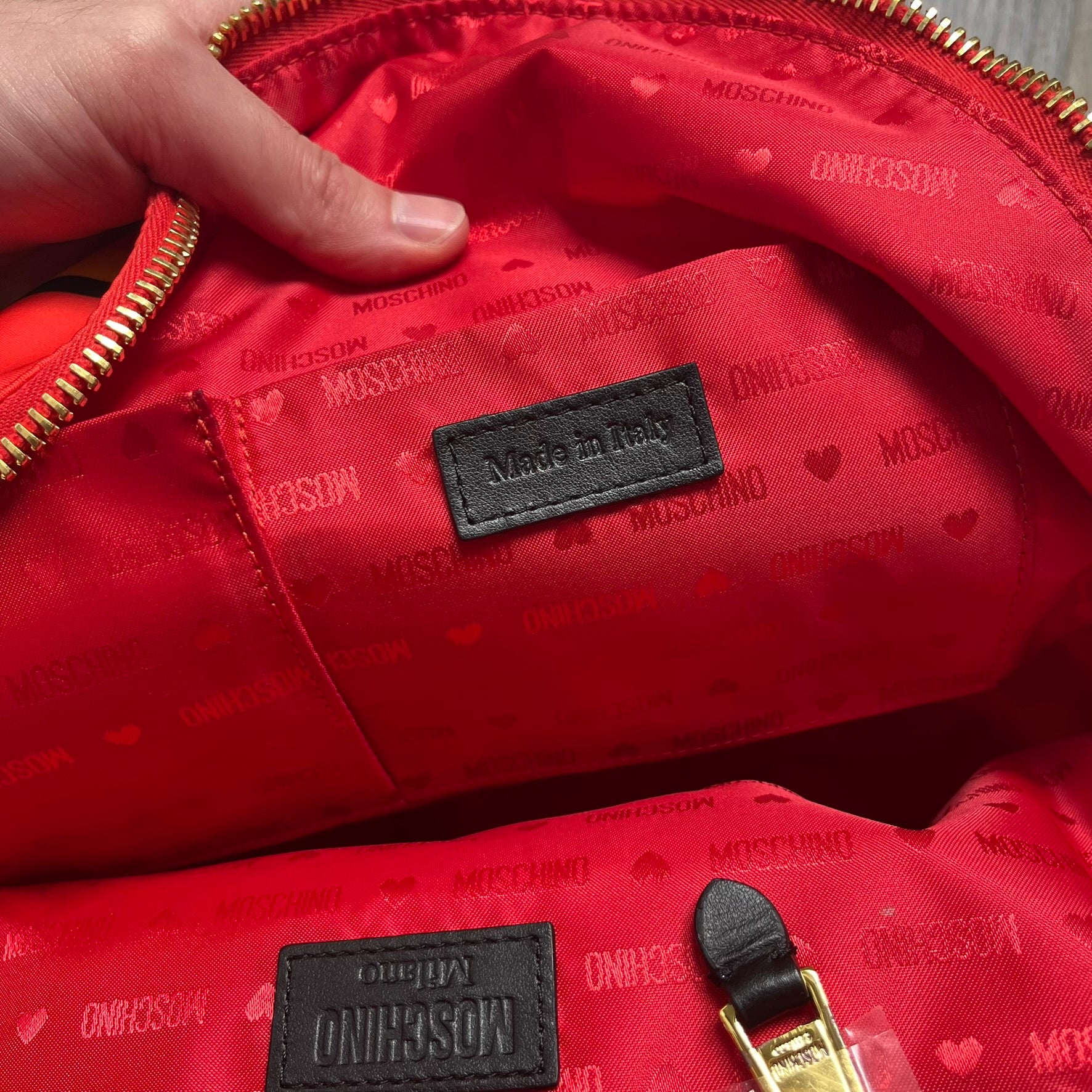 Moschino FW14 McDonald’s Fast Food Backpack is a red nylon backpack from the Autumn/Winter 2014 collection, designed by Jeremy Scott for his debut Moschino lineup. The front features yellow curved arches inspired by McDonald’s branding, with a front zip pocket printed with yellow Moschino text and black “Over 20 Billion Served” slogan. The bag includes gold-tone zippers with black leather pulls, black straps with Moschino logos, a branded interior lining, and comes with a Moschino dust bag. Made in Italy.