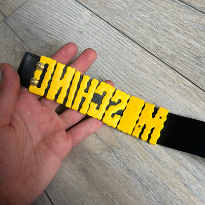 Moschino FW14 SpongeBob Leather Belt is a black leather belt from the Fall/Winter 2014 SpongeBob SquarePants collaboration. The front features the MOSCHINO logo formed by individual movable letters rather than a single rigid buckle. Each letter is finished in yellow with green sponge-like detailing, and the first “O” includes SpongeBob’s happy face. The belt uses a metal buckle closure and comes with the original dust bag and tags. Made in Italy from Genuine Leather.