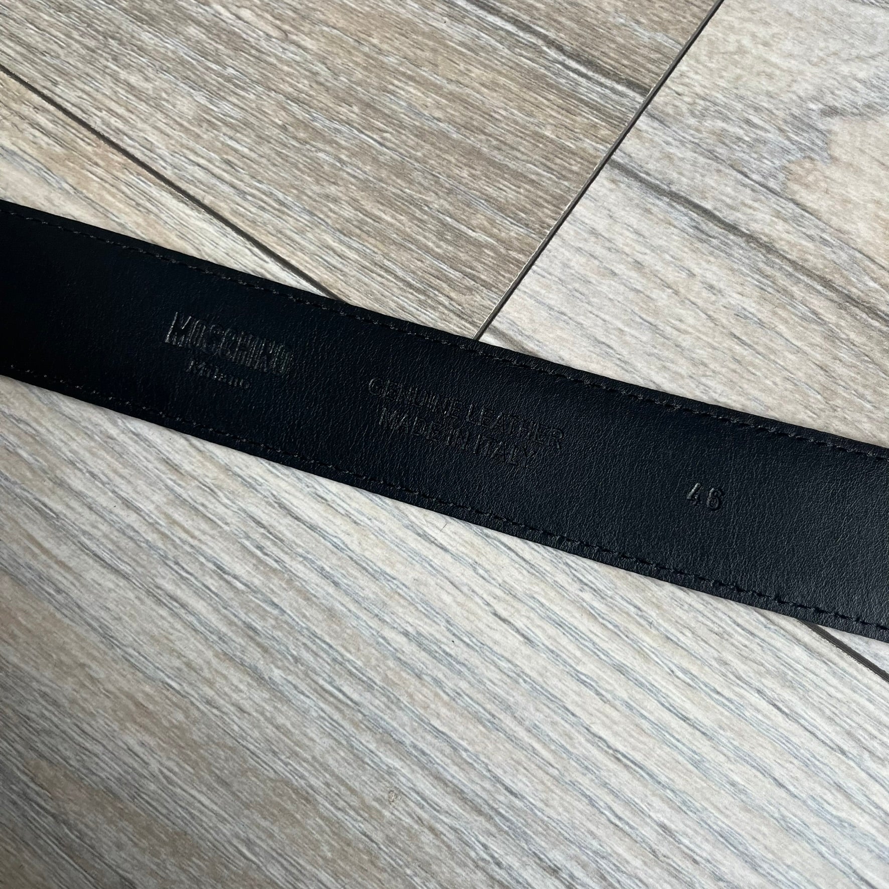 Moschino FW14 SpongeBob Leather Belt is a black leather belt from the Fall/Winter 2014 SpongeBob SquarePants collaboration. The front features the MOSCHINO logo formed by individual movable letters rather than a single rigid buckle. Each letter is finished in yellow with green sponge-like detailing, and the first “O” includes SpongeBob’s happy face. The belt uses a metal buckle closure and comes with the original dust bag and tags. Made in Italy from Genuine Leather.