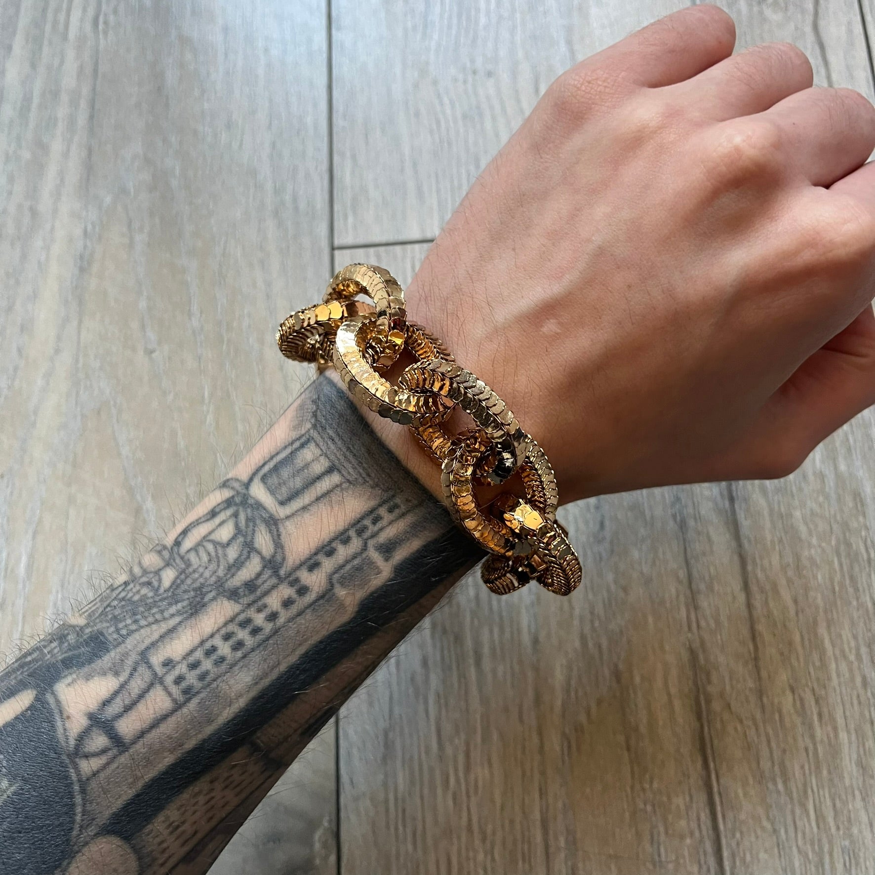 Moschino x H&M 2018 Gold Bracelet is a chunky chain bracelet released as part of the Moschino x H&M collaboration designed by Jeremy Scott. The bracelet features oversized O-shaped links in a gold-tone finish and a T-bar clasp closure. Produced for the 2018 capsule collection and made in Vietnam, it comes with the original white H&MOSCHINO box.