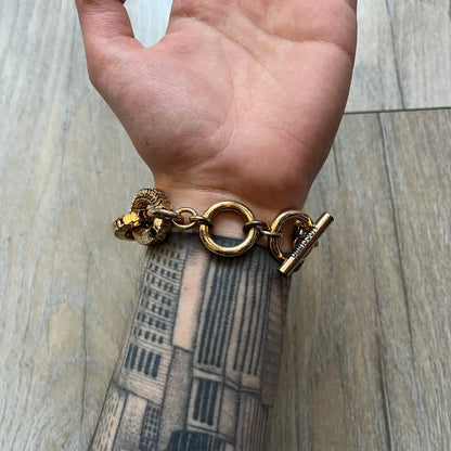 Moschino x H&M 2018 Gold Bracelet is a chunky chain bracelet released as part of the Moschino x H&M collaboration designed by Jeremy Scott. The bracelet features oversized O-shaped links in a gold-tone finish and a T-bar clasp closure. Produced for the 2018 capsule collection and made in Vietnam, it comes with the original white H&MOSCHINO box.