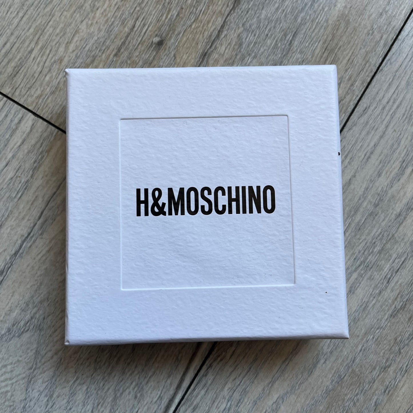 Moschino x H&M 2018 Gold Bracelet is a chunky chain bracelet released as part of the Moschino x H&M collaboration designed by Jeremy Scott. The bracelet features oversized O-shaped links in a gold-tone finish and a T-bar clasp closure. Produced for the 2018 capsule collection and made in Vietnam, it comes with the original white H&MOSCHINO box.