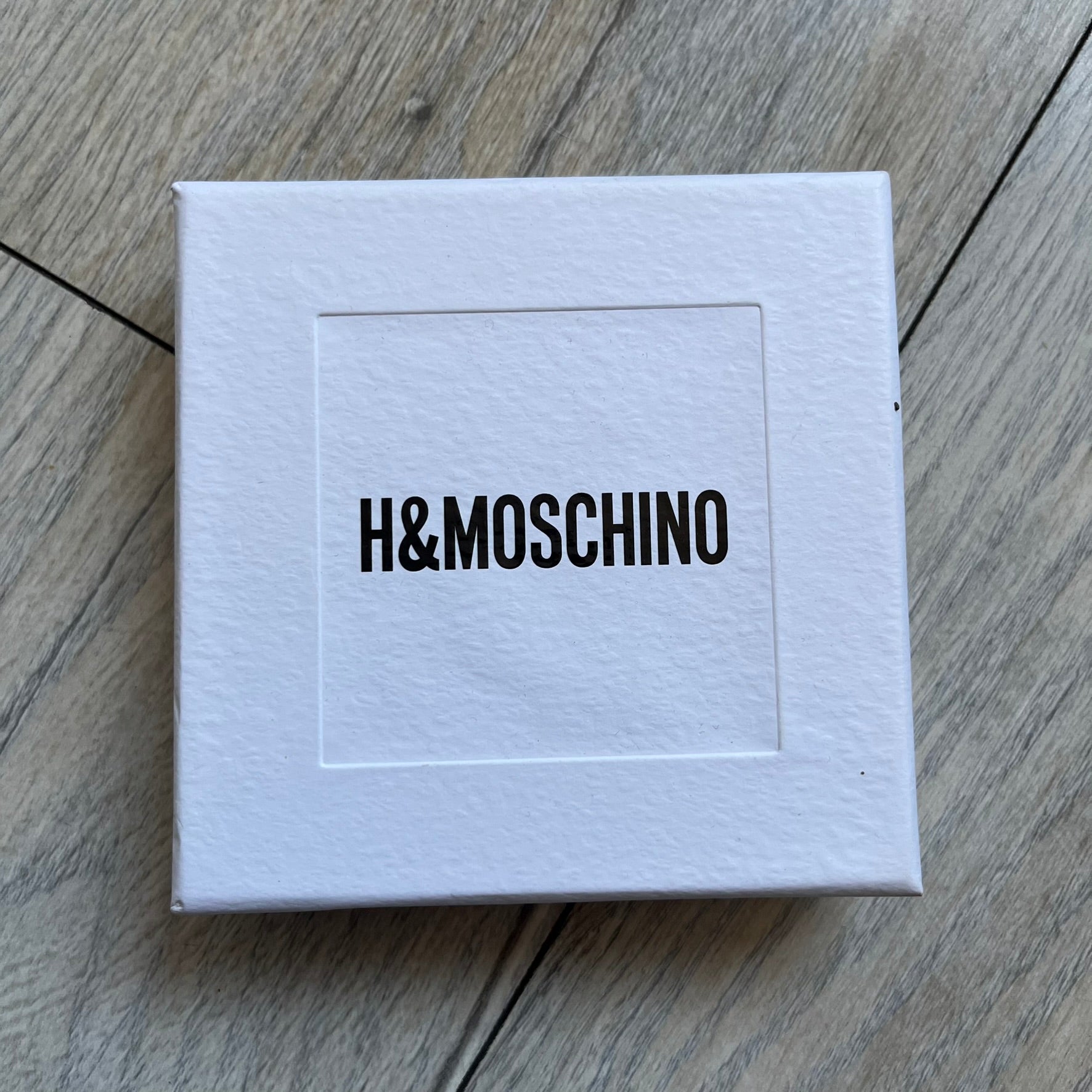 Moschino x H&M 2018 Gold Bracelet is a chunky chain bracelet released as part of the Moschino x H&M collaboration designed by Jeremy Scott. The bracelet features oversized O-shaped links in a gold-tone finish and a T-bar clasp closure. Produced for the 2018 capsule collection and made in Vietnam, it comes with the original white H&MOSCHINO box.