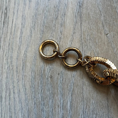 Moschino x H&M 2018 Gold Bracelet is a chunky chain bracelet released as part of the Moschino x H&M collaboration designed by Jeremy Scott. The bracelet features oversized O-shaped links in a gold-tone finish and a T-bar clasp closure. Produced for the 2018 capsule collection and made in Vietnam, it comes with the original white H&MOSCHINO box.