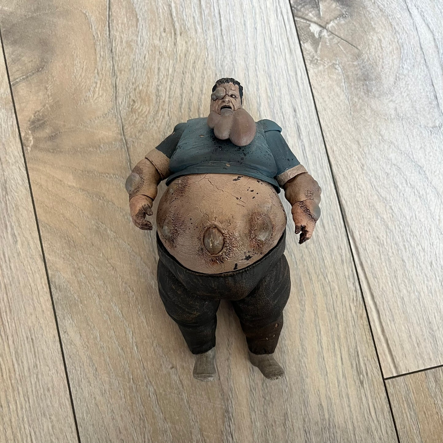 NECA Left 4 Dead Boomer Action Figure is a plastic figure released in September 2012, based on the Boomer character from the Left 4 Dead game. The figure features detailed sculpting with articulated arms and legs for adjustable posing. NECA and Valve markings are present on the underside of the feet.