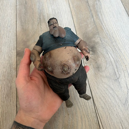 NECA Left 4 Dead Boomer Action Figure is a plastic figure released in September 2012, based on the Boomer character from the Left 4 Dead game. The figure features detailed sculpting with articulated arms and legs for adjustable posing. NECA and Valve markings are present on the underside of the feet.