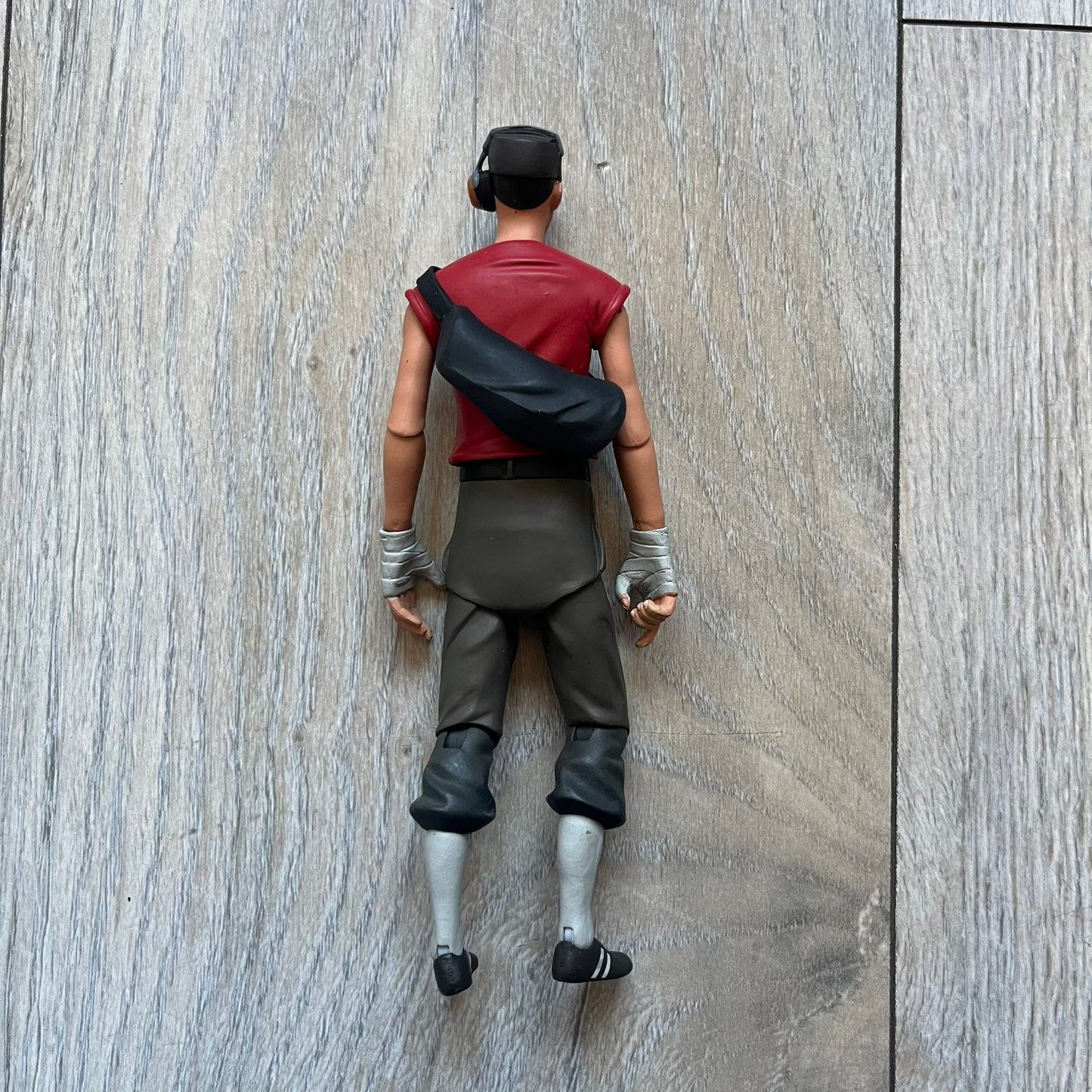 NECA Team Fortress 2 RED Scout Series 4 action figure from 2018. The figure measures approximately 7 inches in scale and recreates the Scout character from Valve’s Team Fortress 2 with game-accurate styling. It features more than 25 points of articulation and comes with three weapons: a scattergun, pistol, and bat.
