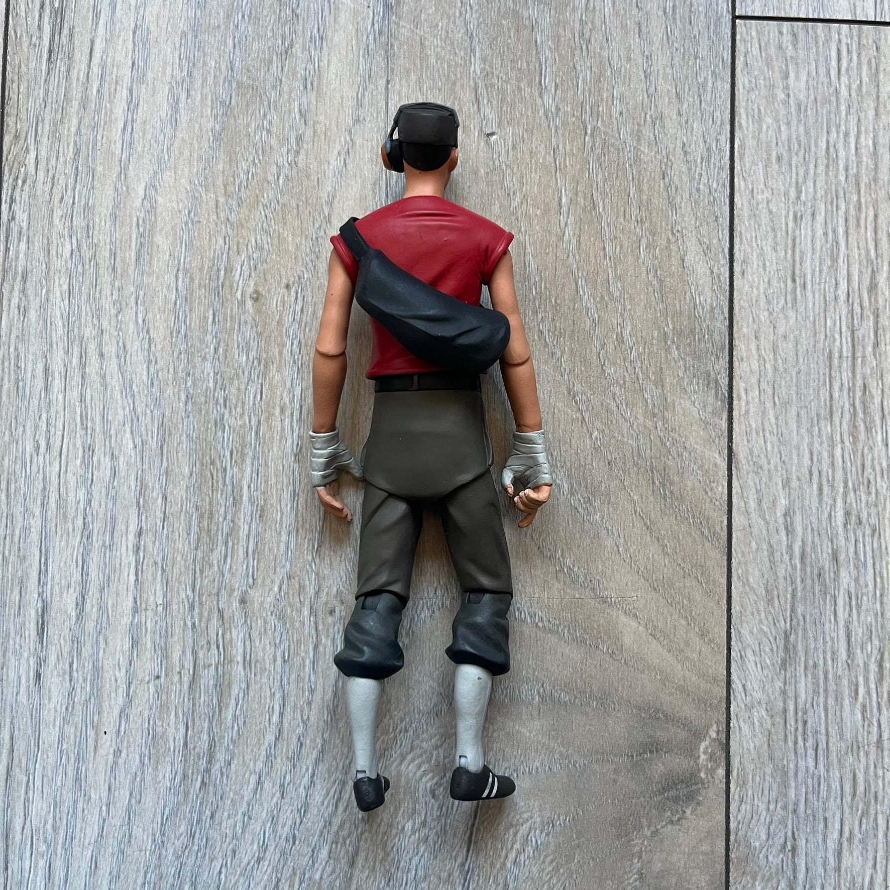 NECA Team Fortress 2 RED Scout Series 4 action figure from 2018. The figure measures approximately 7 inches in scale and recreates the Scout character from Valve’s Team Fortress 2 with game-accurate styling. It features more than 25 points of articulation and comes with three weapons: a scattergun, pistol, and bat.