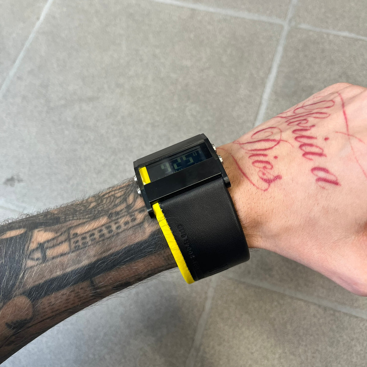 Nike 10//2 Lance Armstrong 2005 Signature Digital Watch features a black stainless steel case with a black LCD display and a black waterproof leather strap with a bright yellow accent. It has a 100-hour chronograph, interval timer, three time alarms, hydration alarm, and data recall, with water resistance to 100 meters. The strap has engraved date and time markings, and the watch comes with the original box and papers.
