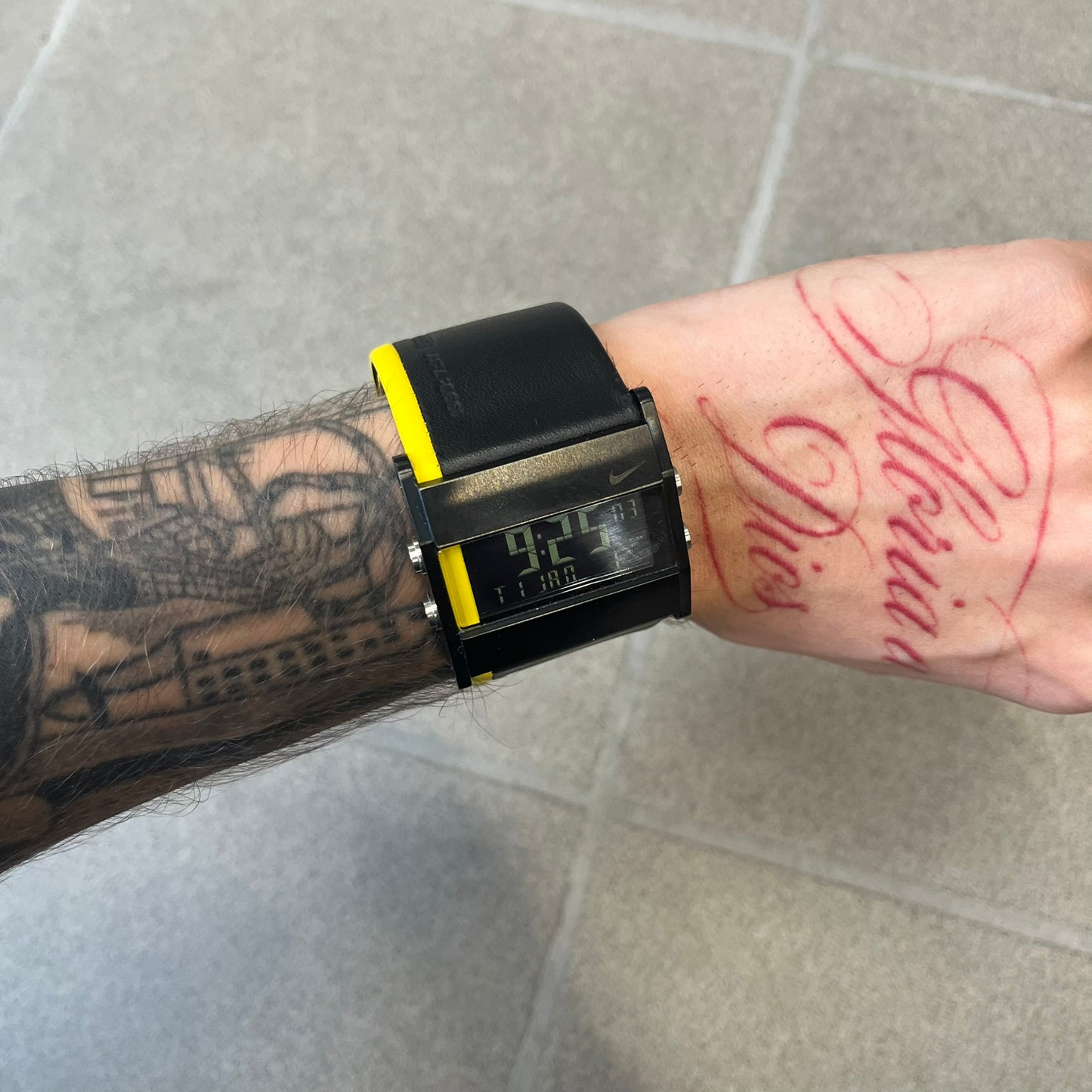 Nike 10//2 Lance Armstrong 2005 Signature Digital Watch features a black stainless steel case with a black LCD display and a black waterproof leather strap with a bright yellow accent. It has a 100-hour chronograph, interval timer, three time alarms, hydration alarm, and data recall, with water resistance to 100 meters. The strap has engraved date and time markings, and the watch comes with the original box and papers.
