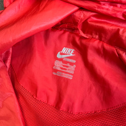 Nike 2000s Black Stars Red Windbreaker features a two-tone red design with a lighter red upper section and a darker red lower half. It is detailed with black star patches running along one sleeve and an additional star patch on the front. The jacket includes two zip pockets.