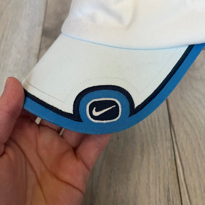 Nike 2000s Blue & White Tennis Visor is a youth-size visor cap featuring a white crown with blue trim running along the edge. The front includes a navy and white Nike logo, while the underside of the brim is finished in blue. The visor is designed with a soft, comfortable headband-style strap for a secure fit.