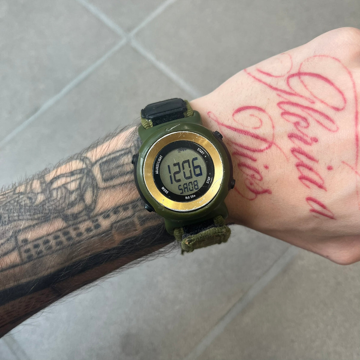 Nike 2000's Gorge Sport WK0013 Digital Watch is a vintage digital watch featuring a green circular face framed by a gold ring, water resistant up to 50m. It's fitted with a green canvas strap accented with orange line patterns and a black leather tab bearing the Nike logo.
