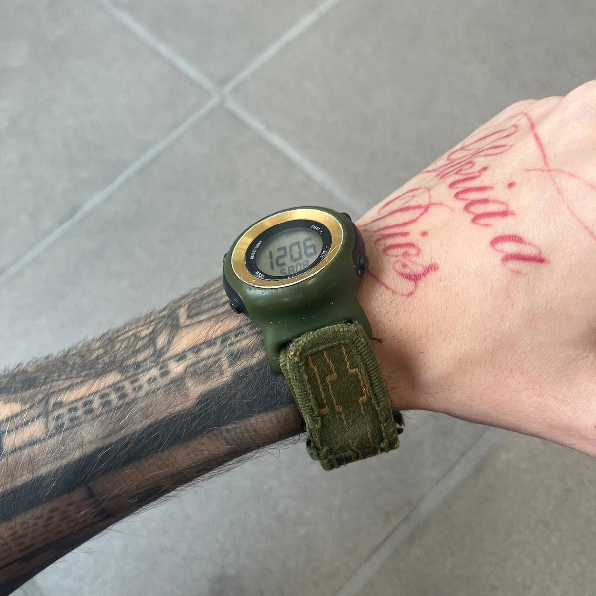 Nike 2000's Gorge Sport WK0013 Digital Watch is a vintage digital watch featuring a green circular face framed by a gold ring, water resistant up to 50m. It's fitted with a green canvas strap accented with orange line patterns and a black leather tab bearing the Nike logo.