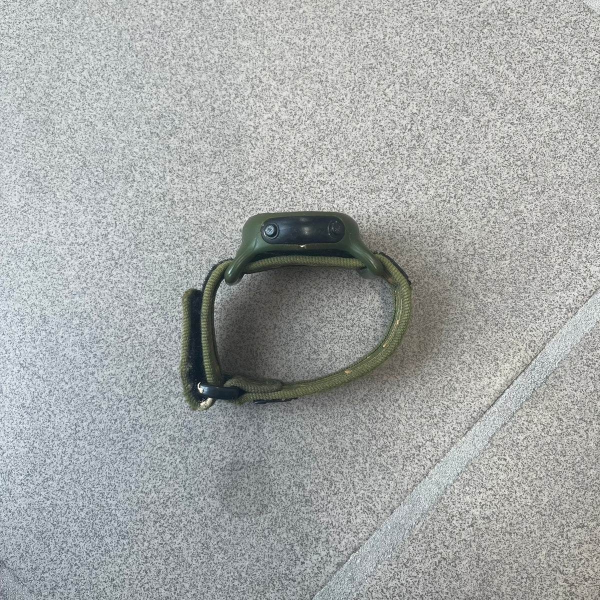 Nike 2000's Gorge Sport WK0013 Digital Watch is a vintage digital watch featuring a green circular face framed by a gold ring, water resistant up to 50m. It's fitted with a green canvas strap accented with orange line patterns and a black leather tab bearing the Nike logo.