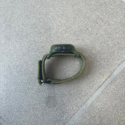 Nike 2000's Gorge Sport WK0013 Digital Watch is a vintage digital watch featuring a green circular face framed by a gold ring, water resistant up to 50m. It's fitted with a green canvas strap accented with orange line patterns and a black leather tab bearing the Nike logo.