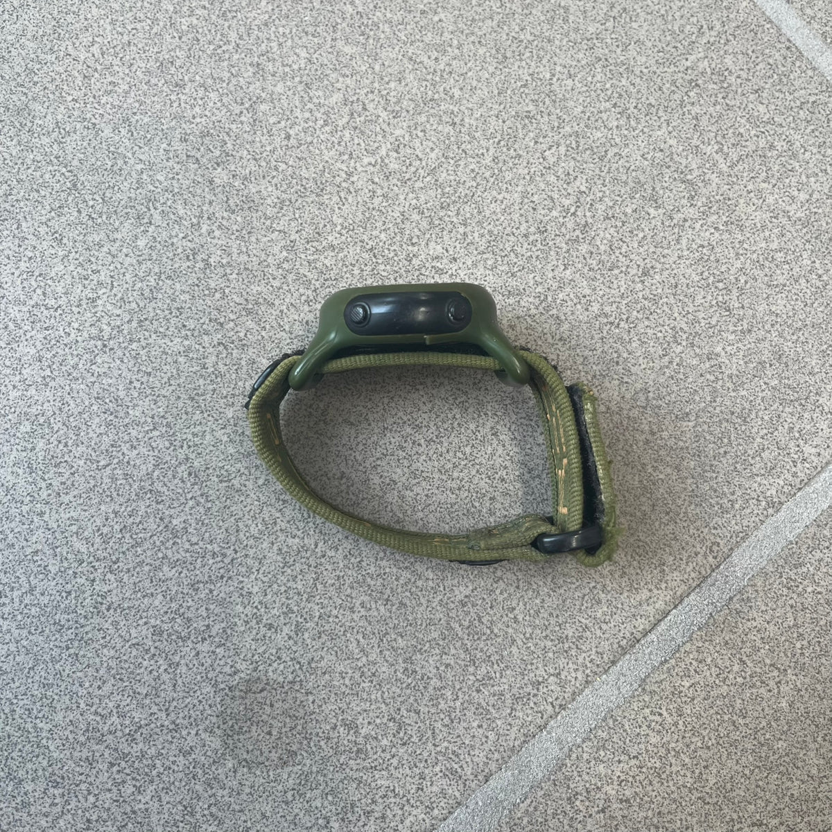Nike 2000's Gorge Sport WK0013 Digital Watch is a vintage digital watch featuring a green circular face framed by a gold ring, water resistant up to 50m. It's fitted with a green canvas strap accented with orange line patterns and a black leather tab bearing the Nike logo.