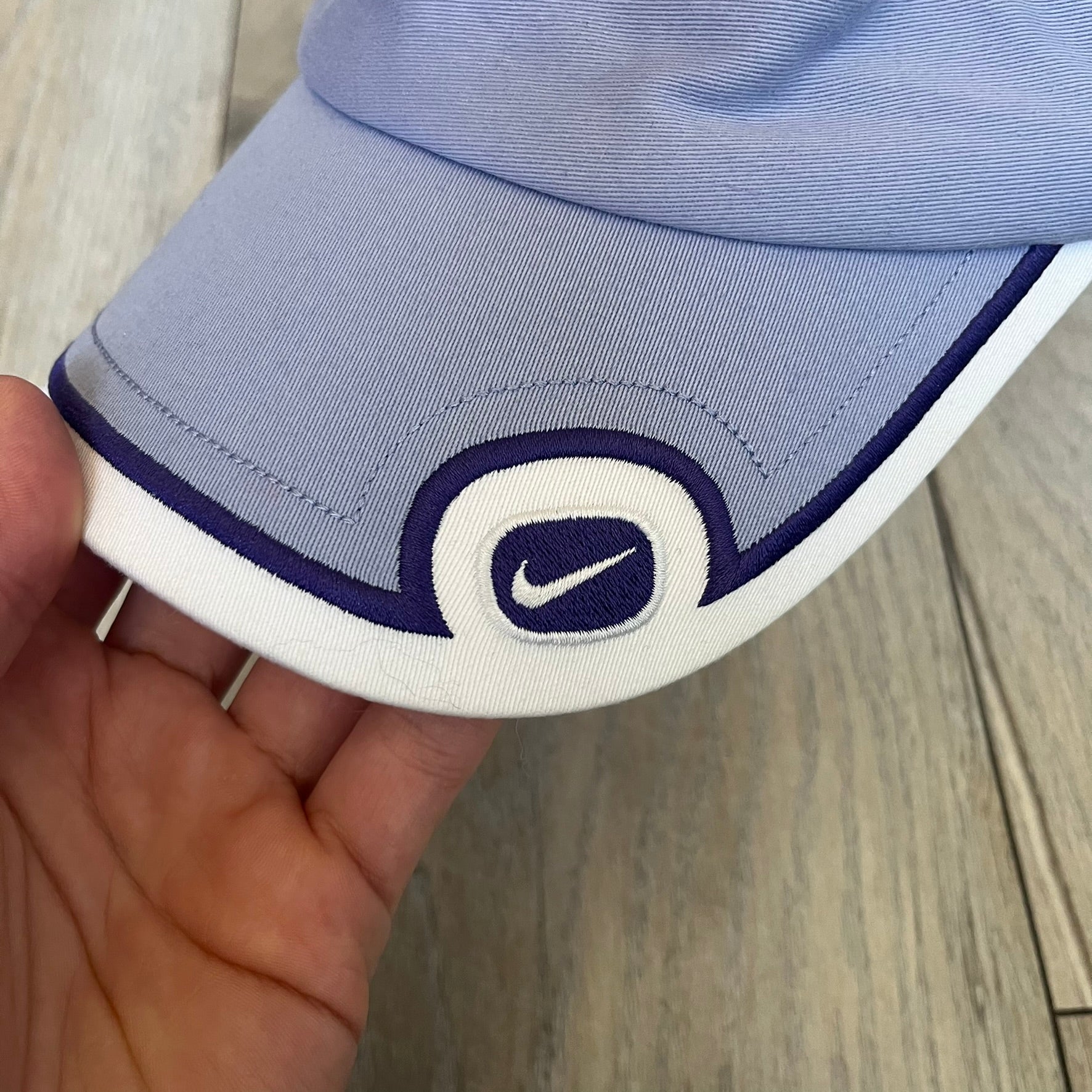 Nike 2000s Violet &amp; White Tennis Visor is a youth-size visor cap featuring a violet crown with white trim running along the edge. The front includes a purple and white Nike logo, while the underside of the brim is finished in white. The visor is designed with a soft, comfortable headband-style strap for a secure fit.