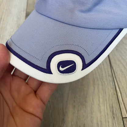 Nike 2000s Violet &amp; White Tennis Visor is a youth-size visor cap featuring a violet crown with white trim running along the edge. The front includes a purple and white Nike logo, while the underside of the brim is finished in white. The visor is designed with a soft, comfortable headband-style strap for a secure fit.