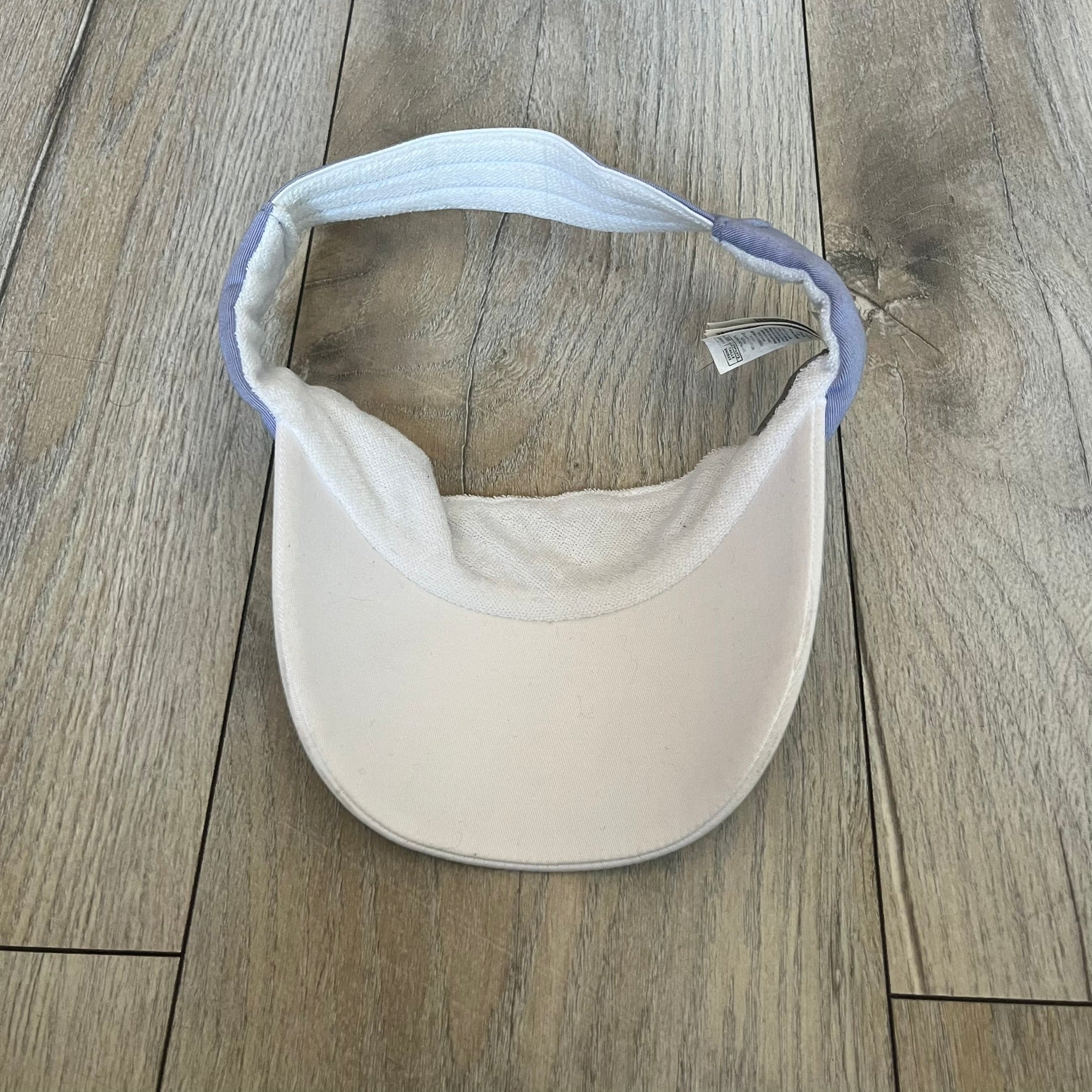 Nike 2000s Violet &amp; White Tennis Visor is a youth-size visor cap featuring a violet crown with white trim running along the edge. The front includes a purple and white Nike logo, while the underside of the brim is finished in white. The visor is designed with a soft, comfortable headband-style strap for a secure fit.