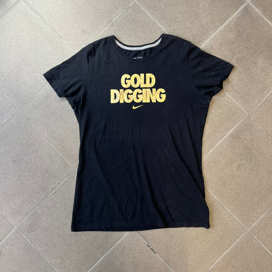 Nike 2012 Olympics “Gold Digging” Black Tee features a black slim-fit T-shirt with gold “Gold Digging” text on the front and a small Nike logo underneath. The design was released in connection with the 2012 Olympics and was later discontinued following controversy surrounding the wording.
