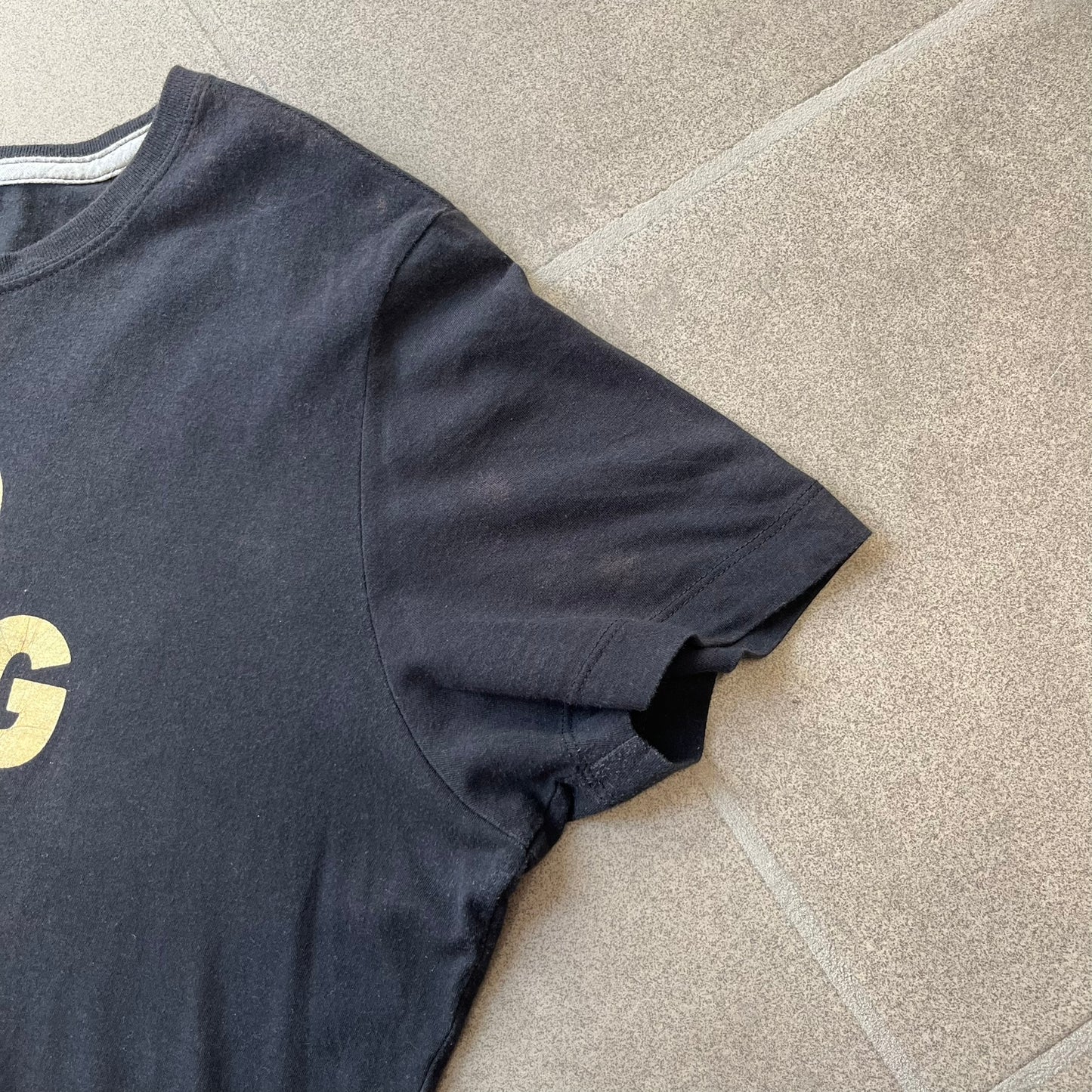 Nike 2012 Olympics “Gold Digging” Black Tee features a black slim-fit T-shirt with gold “Gold Digging” text on the front and a small Nike logo underneath. The design was released in connection with the 2012 Olympics and was later discontinued following controversy surrounding the wording.
