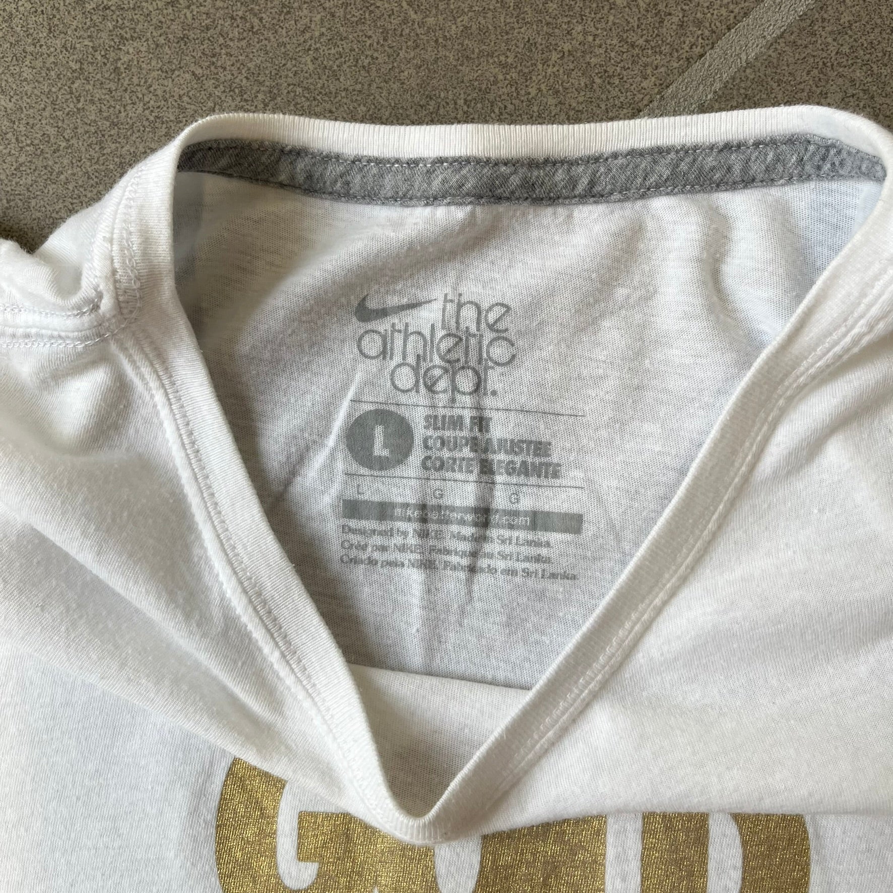 Nike 2012 Olympics “Gold Digging” White Tee features a white slim-fit T-shirt with gold “Gold Digging” text on the front and a small Nike logo underneath. The design was released in connection with the 2012 Olympics and was later discontinued following controversy surrounding the wording.
