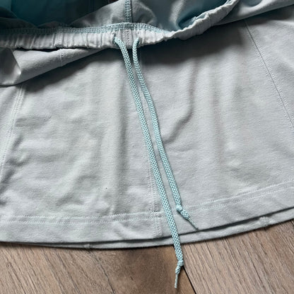 Nike 90’s Challenge Court Tennis Skirt is a baby blue women’s tennis skirt made in Thailand. It features a small green and red Nike Court logo patch at the lower hem, a Dri-FIT patch at the top, and an adjustable waistband with drawstrings.&nbsp;