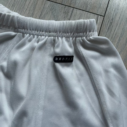 Nike 90’s Challenge Court Tennis Skirt is a white women’s tennis skirt made in USA. It features a small green and red Nike Court logo patch at the lower hem, a Dri-FIT patch at the top, and an adjustable waistband with drawstrings.